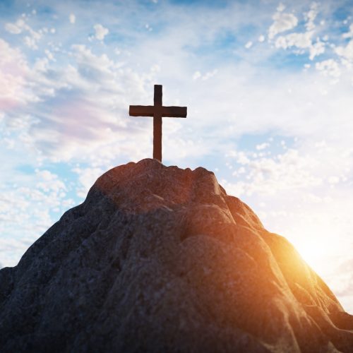 Cross on mountain peak at sunset christian religion